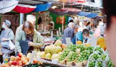 Menschen beim Einkauf auf einem bunten Obstmarkt auf Mallorca, mit frischen Früchten und lebhafter Atmosphäre