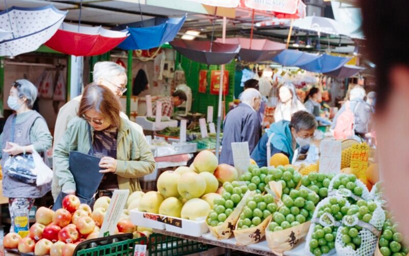 Menschen beim Einkauf auf einem bunten Obstmarkt auf Mallorca, mit frischen Früchten und lebhafter Atmosphäre