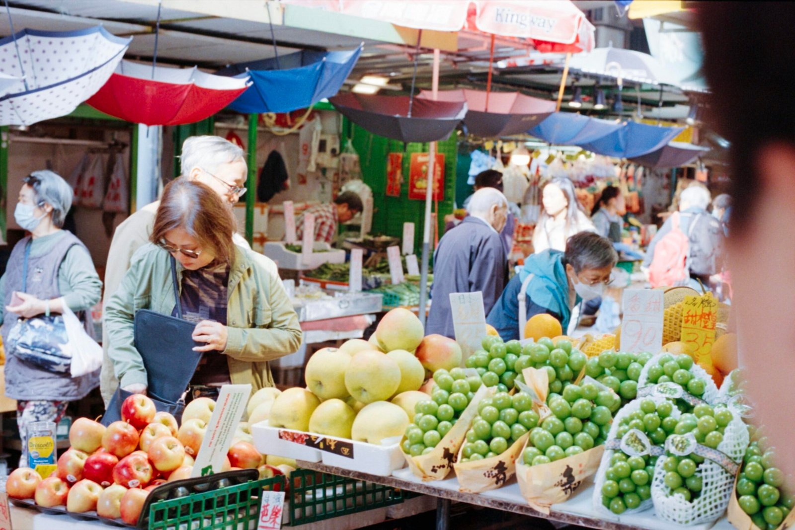 Menschen beim Einkauf auf einem bunten Obstmarkt auf Mallorca, mit frischen Früchten und lebhafter Atmosphäre