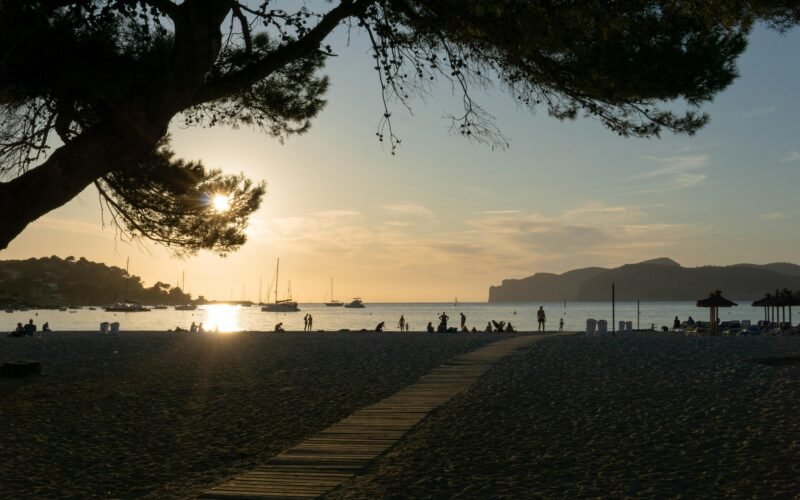 Menschen gehen tagsüber am Ufer entlang auf Mallorca, während Wasser und Himmel sichtbar sind