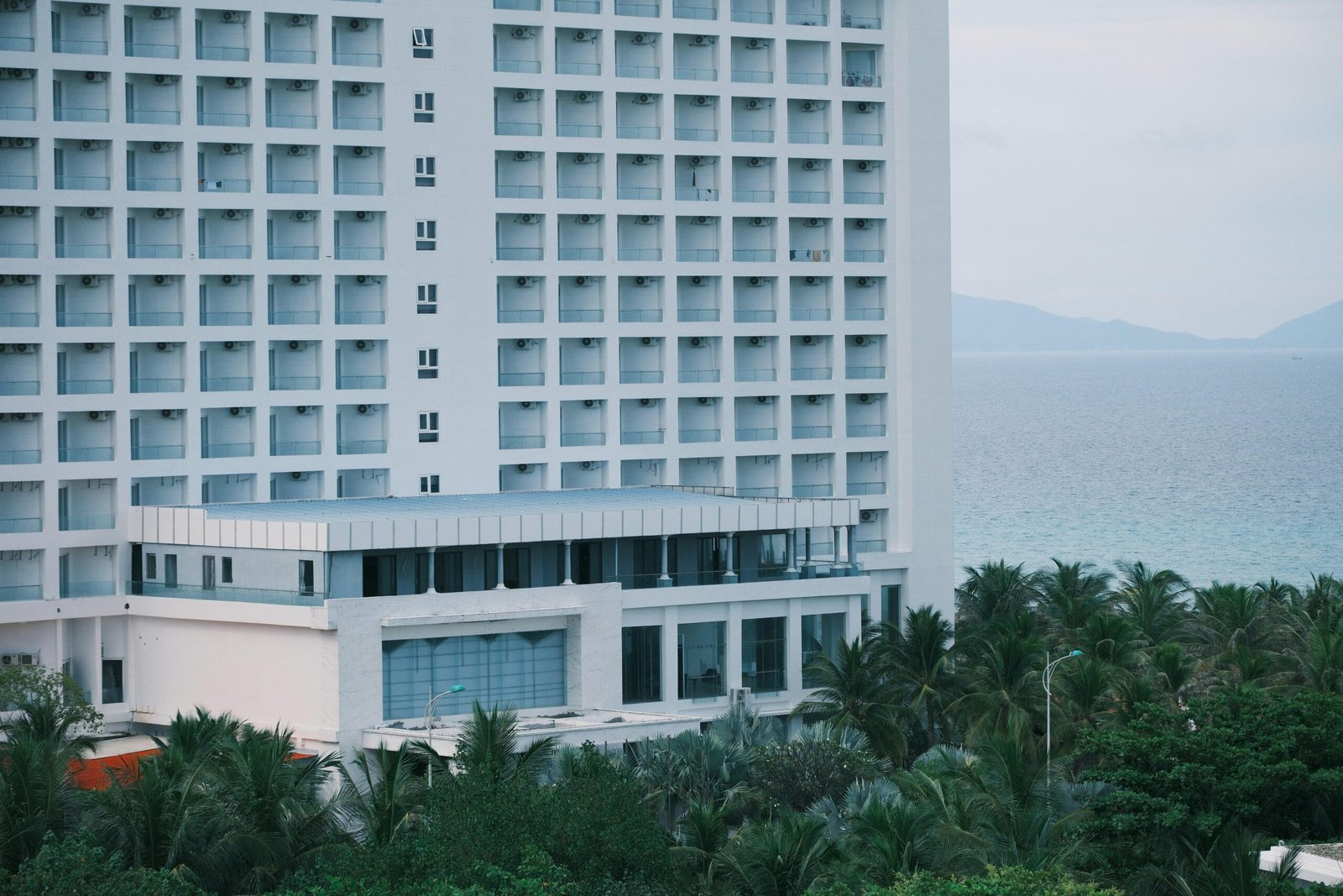 Modernes Hotelgebäude auf Mallorca mit Blick auf den Ozean und Palmen, fotografiert von Duc Van.