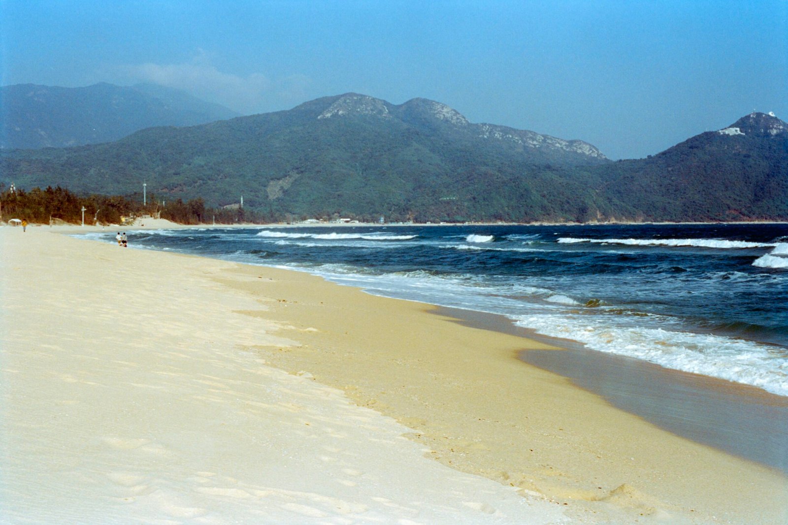 Sandstrand auf Mallorca mit blauen Wellen und Bergen im Hintergrund, aufgenommen von Zhen Yao
