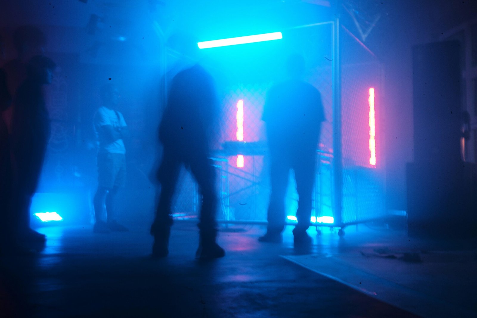 Silhouetten von Menschen in einem Club auf Mallorca, beleuchtet von blauen Neonlichtern, aufgenommen von Rendy Novantino.
