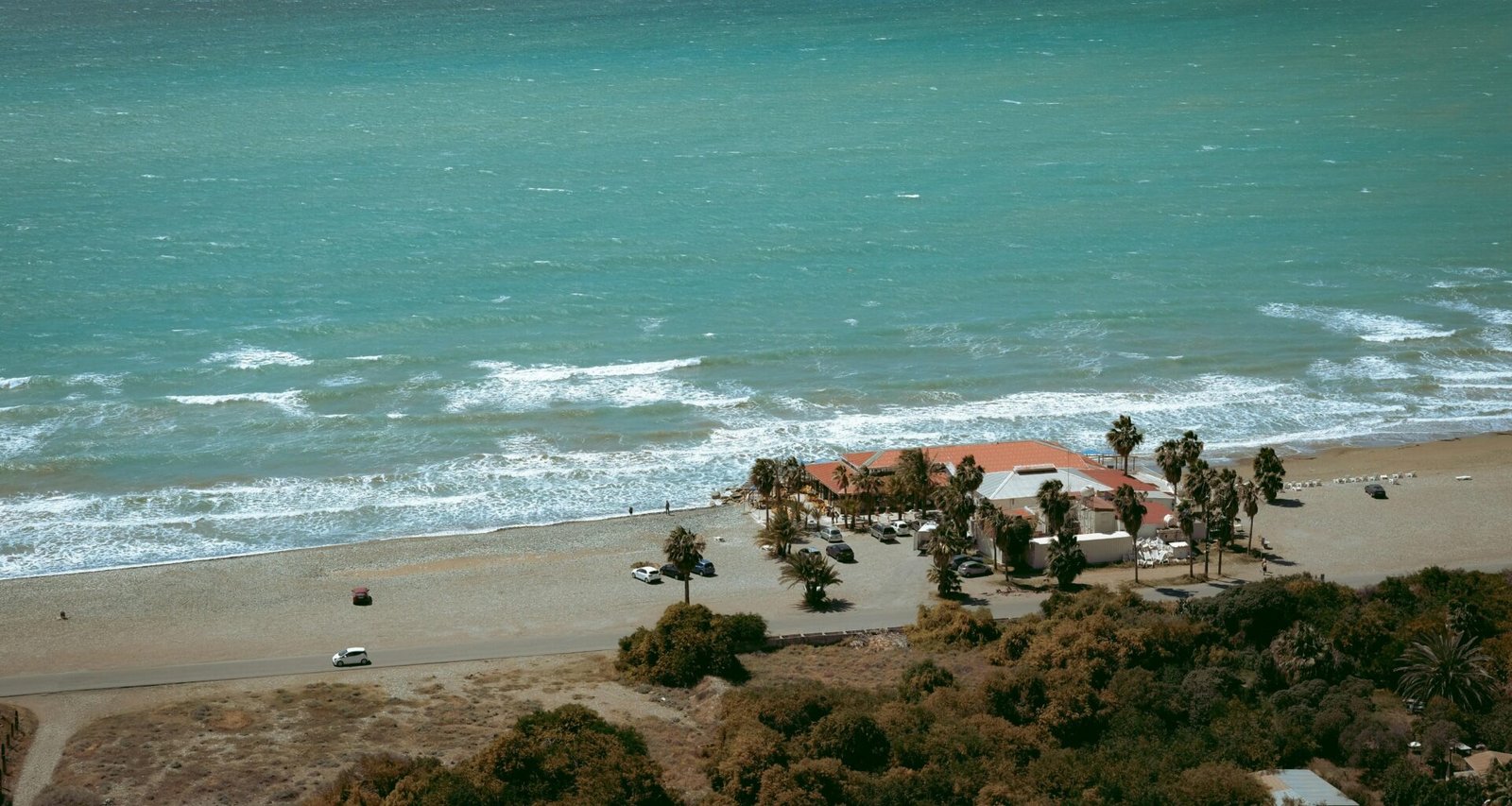 Strandhotel mit Palmen und Wellen auf Mallorca, aufgenommen von Yu Ko