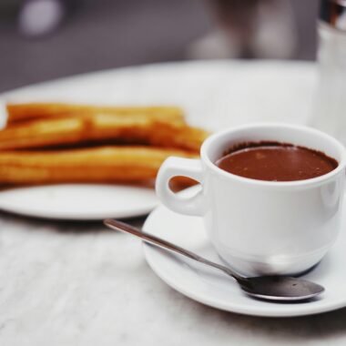 Tasse heiße Schokolade mit einer Platte Churros auf Mallorca, fotografiert von Oscar Nord