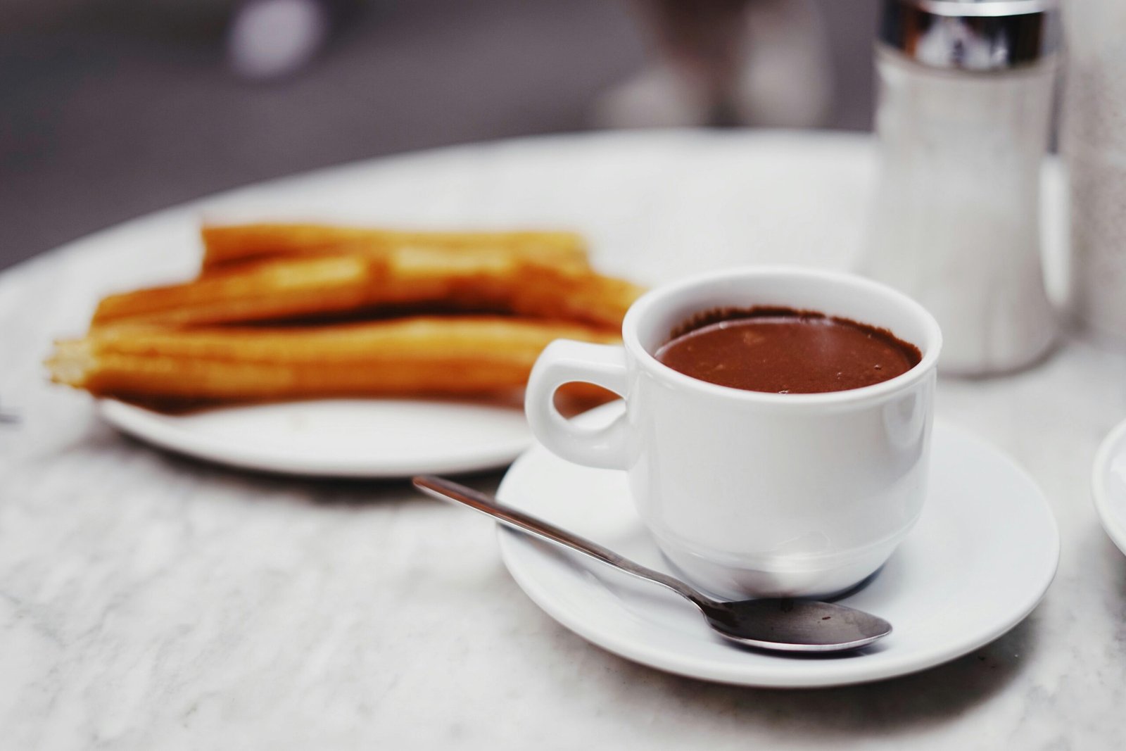 Tasse Schokoladendrink mit einer Platte Churros auf Mallorca, fotografiert von Oscar Nord.