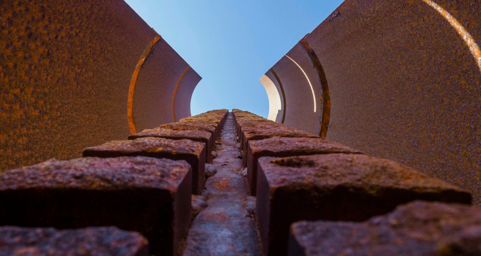 Ein schmaler Weg zwischen Mauern auf Mallorca unter einem klaren blauen Himmel, fotografiert von Alexander Schimmeck.