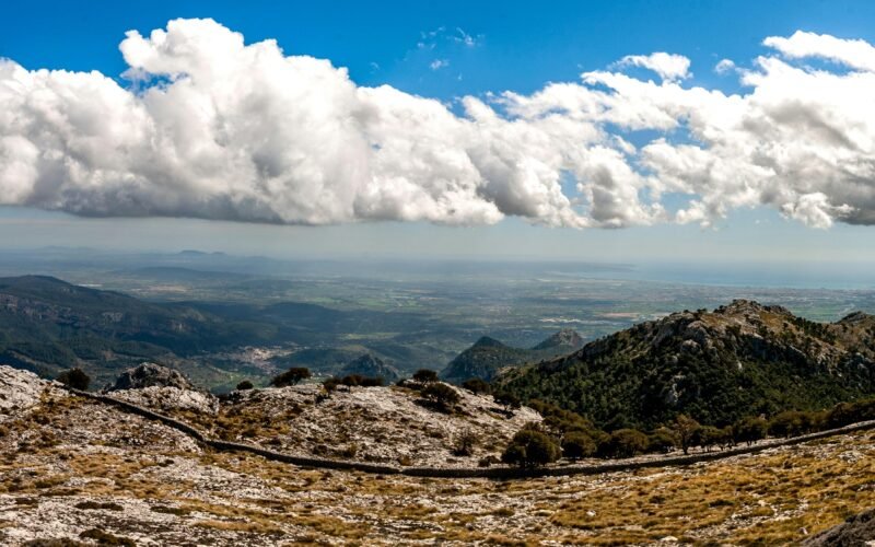 Weiße Wolken ziehen über die braunen Berge auf Mallorca, aufgenommen von David Vives.