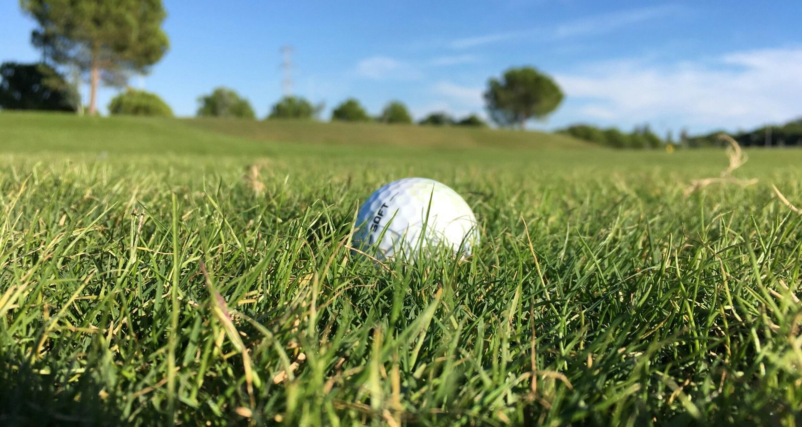 Weißer Golfball liegt auf einem saftig grünen Rasen auf Mallorca, fotografiert von George Bougakov.