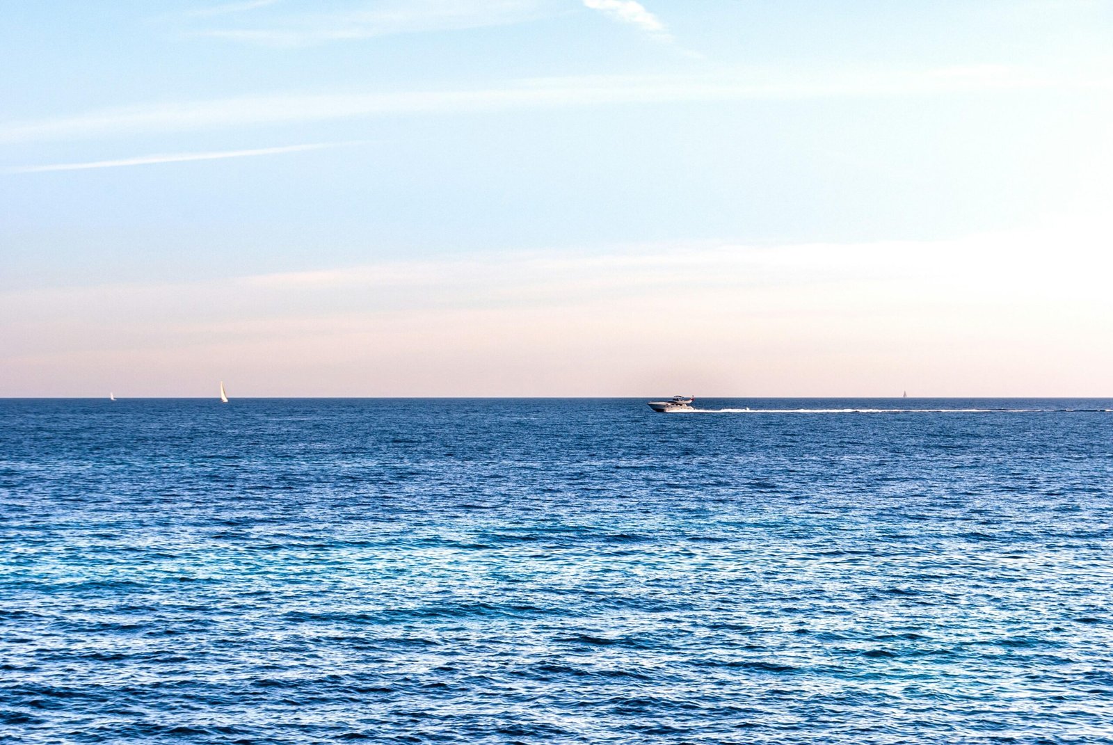 Weißes Boot auf Mallorca auf dem Meer, umgeben von weißen Wolken während des Tages, aufgenommen von David Vives