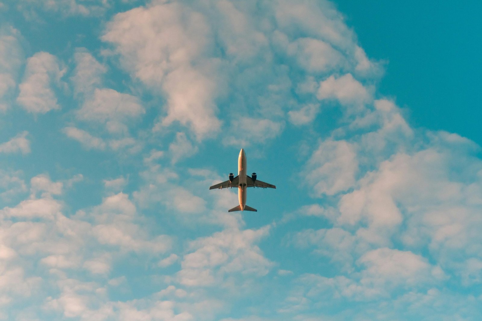 Weißes Flugzeug fliegt tagsüber auf Mallorca durch den blauen Himmel, aufgenommen von Philip Myrtorp.
