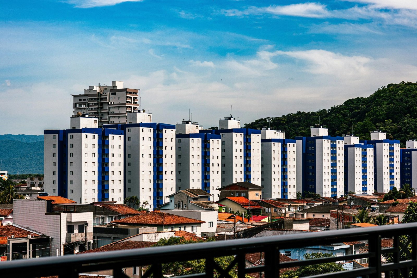 Apartmentgebäude mit blauen Akzenten auf Mallorca unter einem bewölkten Himmel, fotografiert von Juan Pablo