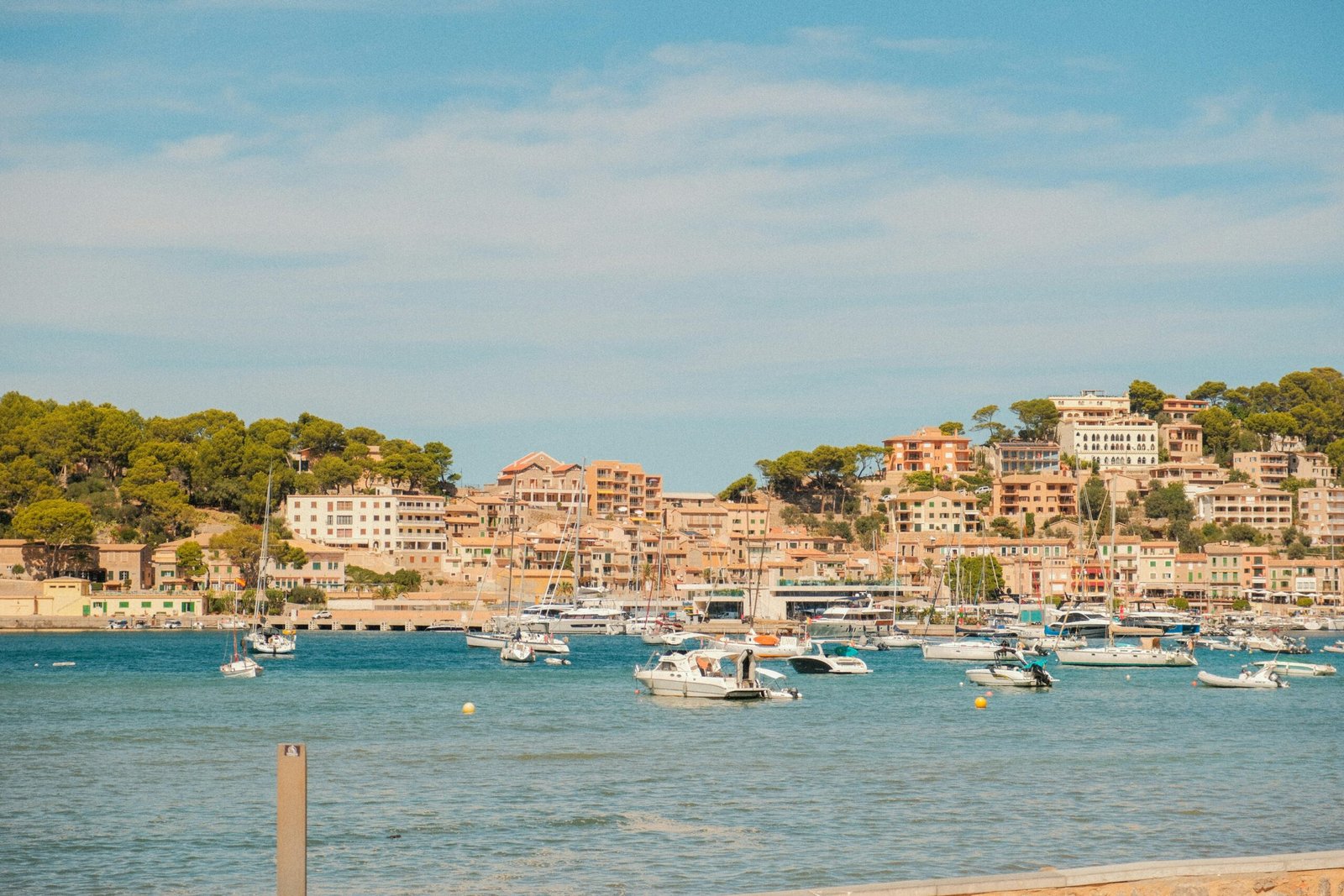 Boote im Hafen auf Mallorca mit einer Stadt auf dem Hügel im Hintergrund, fotografiert von Alexis Presa.
