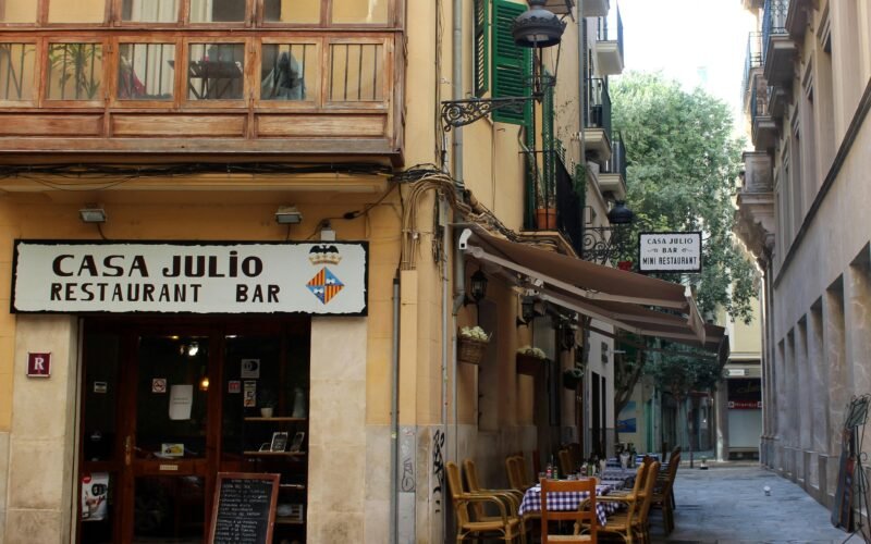 Braune Holzmöbel mit Stühlen und Tischen draußen vor einem Laden auf Mallorca bei Tageslicht
