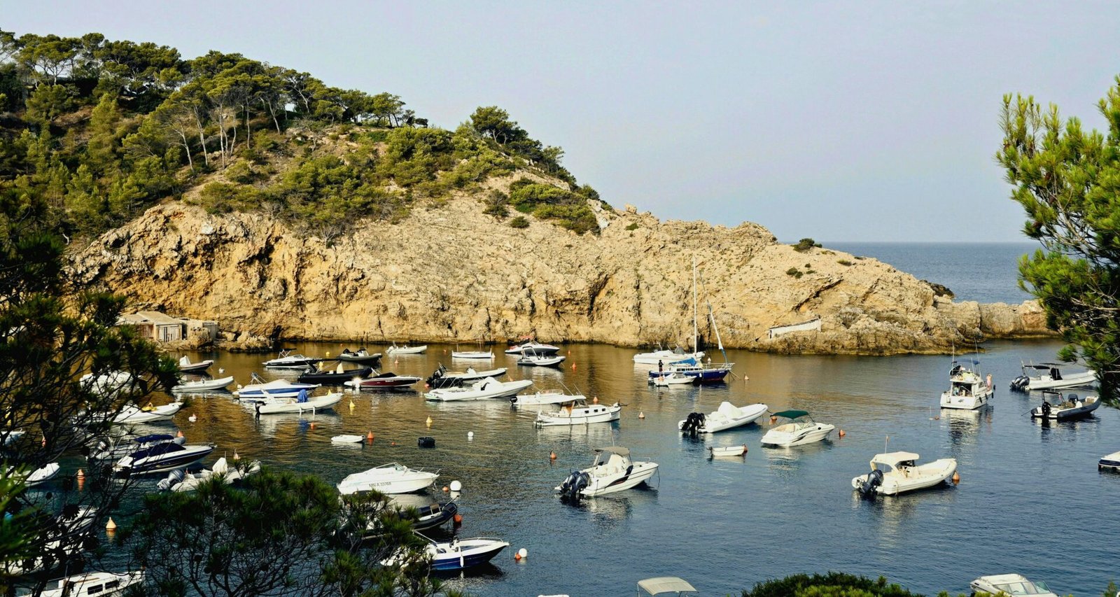 Boote liegen in einem ruhigen Hafen auf Mallorca, umgeben von stiller Wasseroberfläche und Naturkulisse