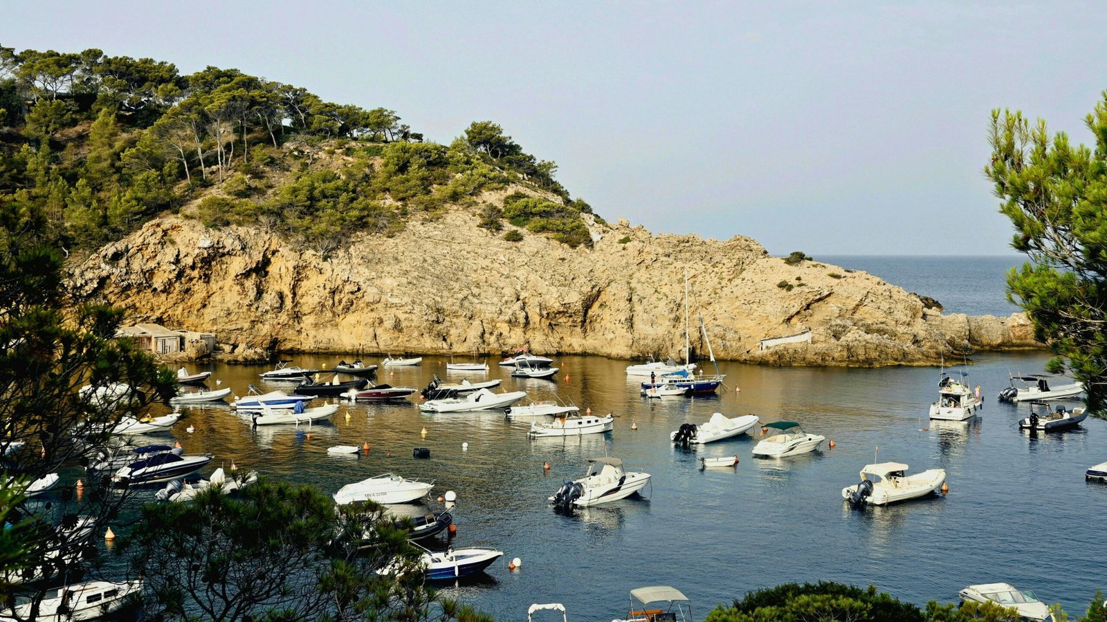 Boote liegen in einem ruhigen Hafen auf Mallorca, umgeben von stiller Wasseroberfläche und Naturkulisse
