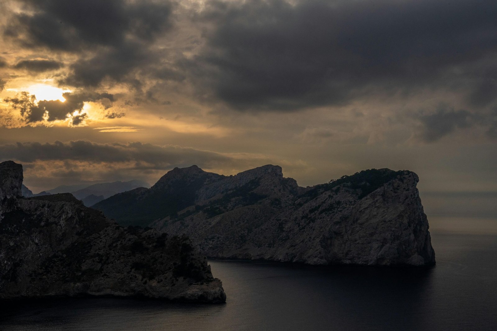 Felsige Küste auf Mallorca unter dunklem, stürmischem Sonnenuntergangshimmel, fotografiert von Tim Bernhard