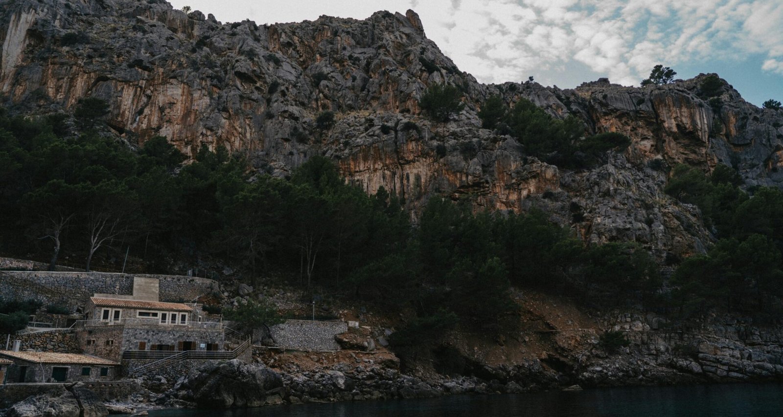 Ein Haus auf einem Berggipfel auf Mallorca, umgeben von natürlicher Landschaft, fotografiert von Raymond Petrik.