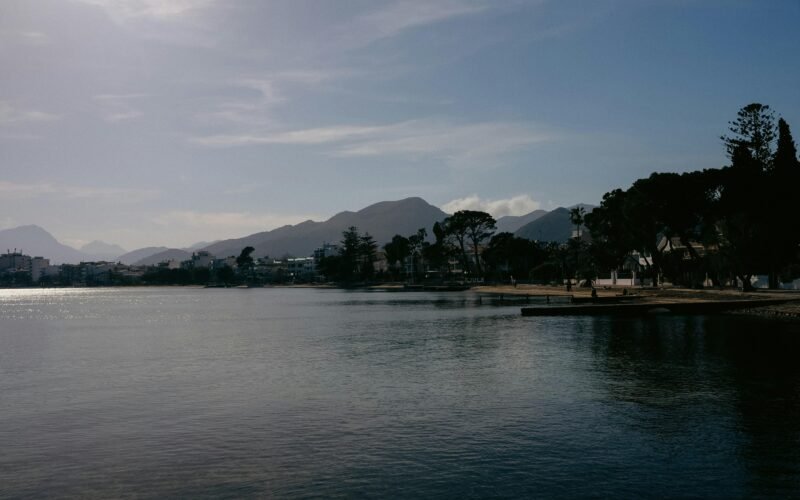 Ein ruhiger Wassersee auf Mallorca, umgeben von Bäumen und Bergen, aufgenommen von Konstantin Chemeris.