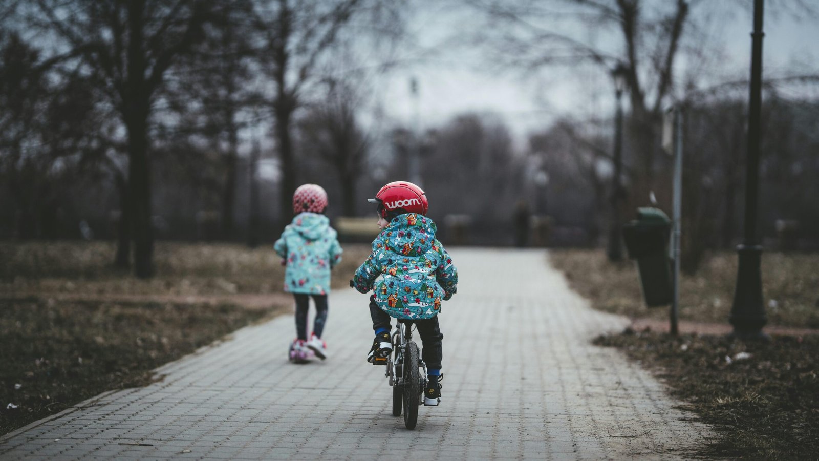 Kinder auf Mallorca, eines fährt Fahrrad, das andere geht auf einem Gehweg neben Bäumen