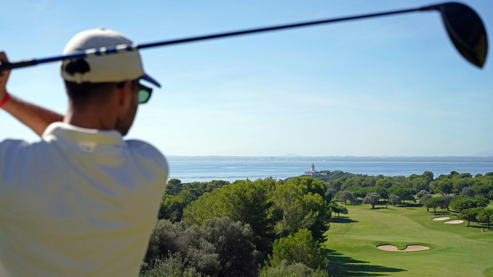 Mann beim Abschlag mit Golfschläger auf einem Golfplatz auf Mallorca, umgeben von grüner Natur