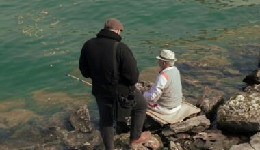 Ein Mann und eine Frau sitzen auf einem Felsen neben Wasser auf Mallorca, fotografiert von Sajad Emad.