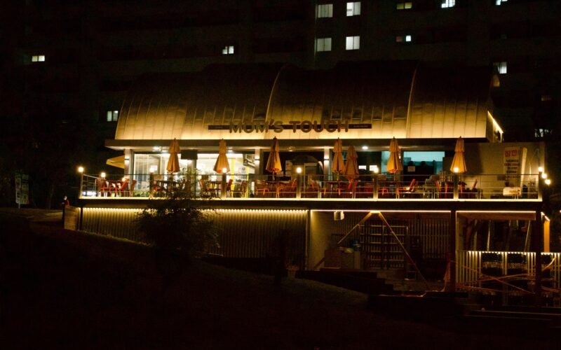 Ein beleuchtetes Restaurant am Flussufer auf Mallorca bei Nacht, mit warmem Licht und ruhiger Atmosphäre