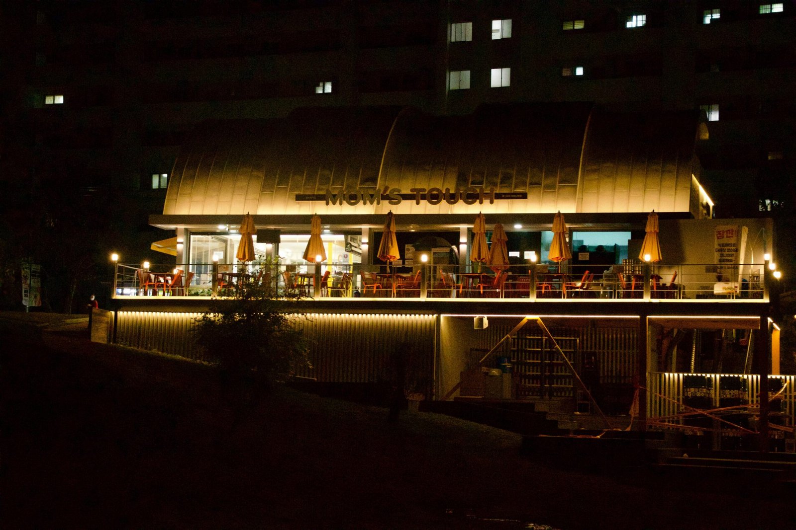 Ein beleuchtetes Restaurant am Flussufer auf Mallorca bei Nacht, mit warmem Licht und ruhiger Atmosphäre