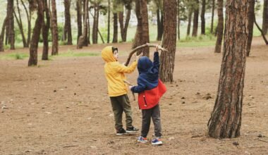 Zwei Kinder stehen nebeneinander im Wald auf Mallorca, umgeben von Bäumen und Natur, aufgenommen von Duygu Güngör.