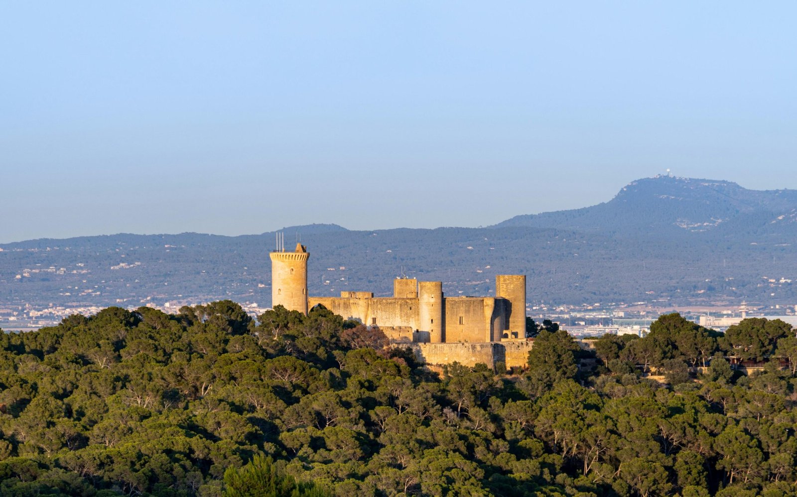Burg auf Mallorca auf einem Hügel, umgeben von Bäumen, aufgenommen von David Vives