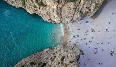 Menschen schwimmen im klaren Wasser an einem Strand auf Mallorca, aufgenommen von Alex Kulikov.