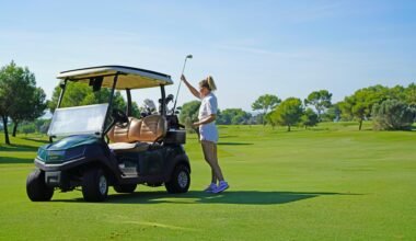Frau steht neben einem Golfwagen auf einem Golfplatz auf Mallorca, umgeben von grünen Fairways und Bäumen.
