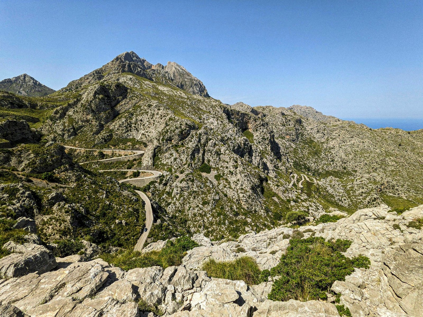 Kurvige Bergstraße auf Mallorca bei Sonnenschein, umgeben von Bergen, fotografiert von Andre Blanco