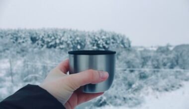 Person hält eine Tasse vor einer verschneiten Landschaft auf Mallorca, aufgenommen von Veronica Mihaylovskaya