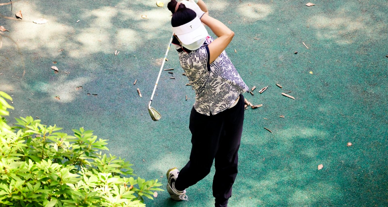 Person hält einen Golfschläger auf Mallorca, bereit zum Abschlag, mit grünem Golfplatz im Hintergrund