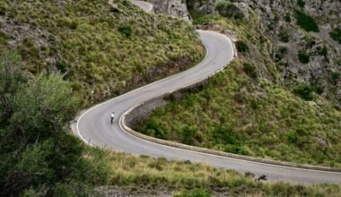 Person fährt mit Motorrad eine kurvige Straße auf Mallorca entlang, umgeben von Natur und Landschaft