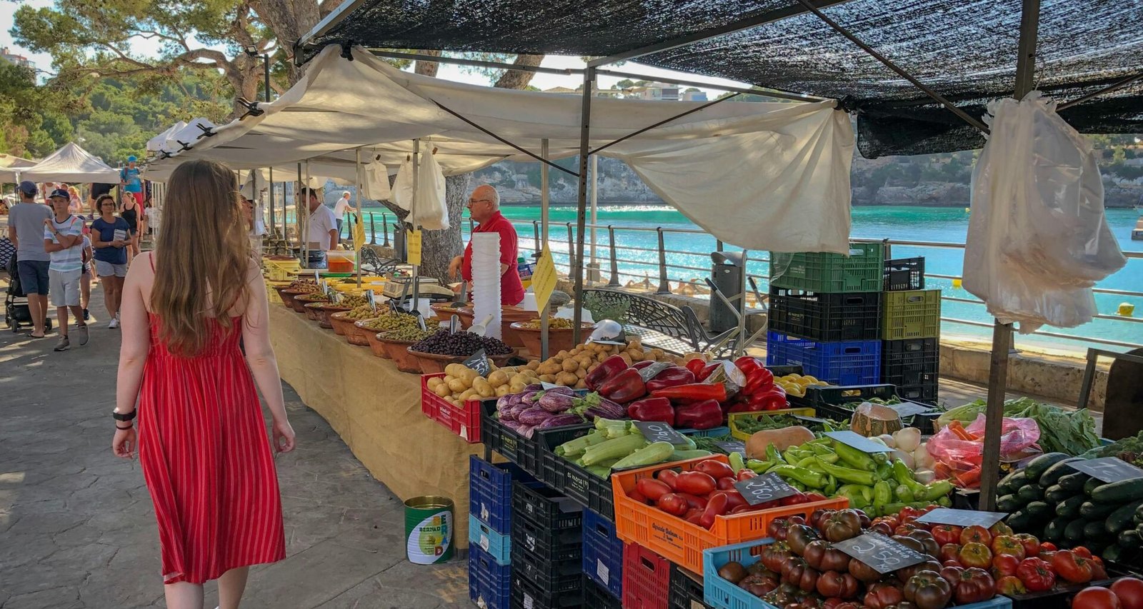Frau läuft an Obst- und Gemüsehändlern auf Mallorca vorbei, lebendiger Markt mit frischen Produkten