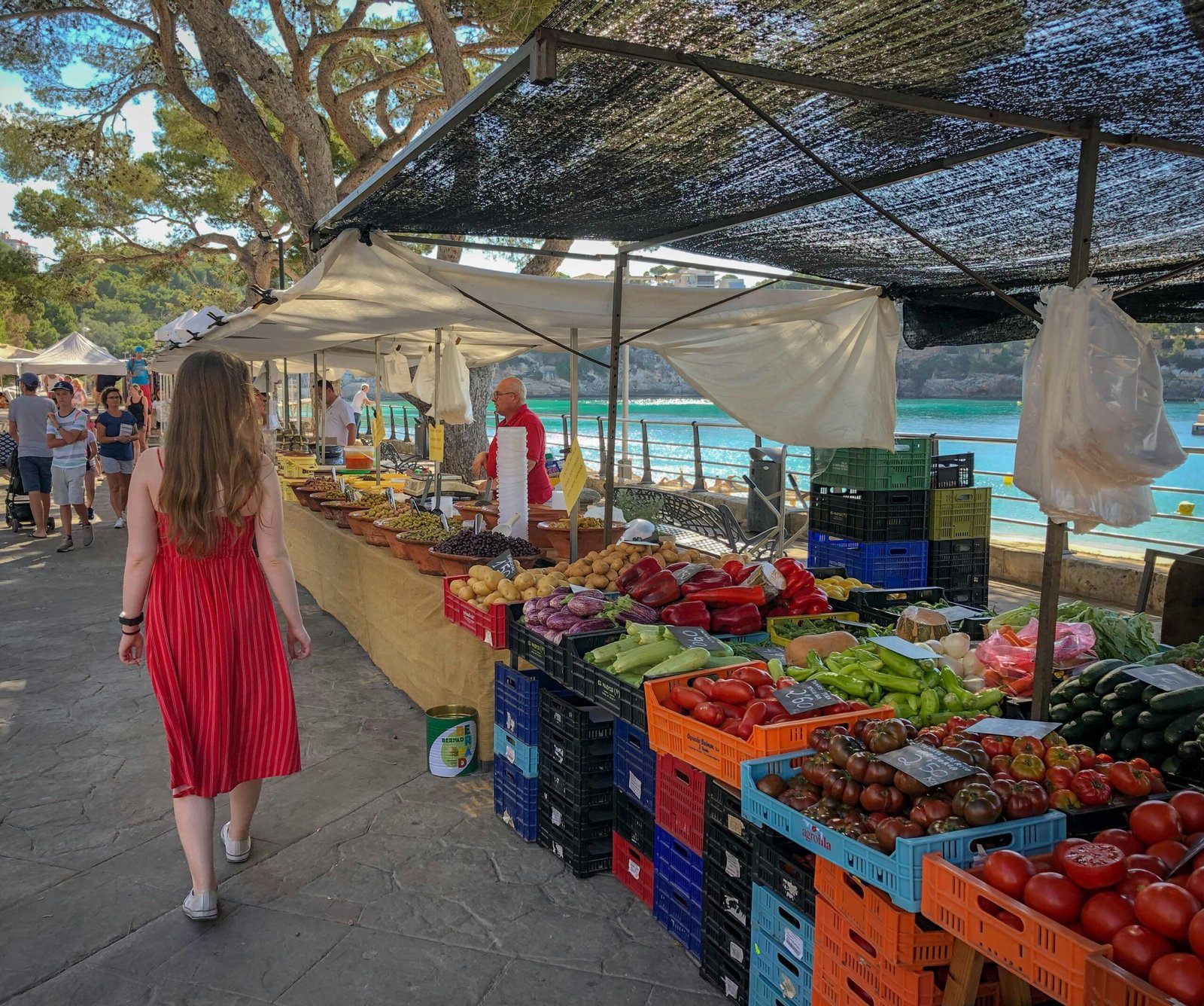 Frau läuft an Obst- und Gemüsehändlern auf Mallorca vorbei, lebendiger Markt mit frischen Produkten