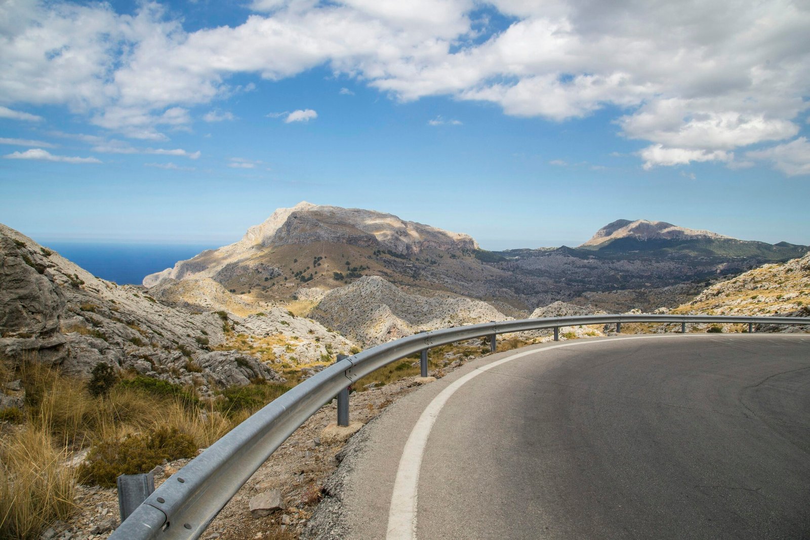 Graue Betonstraße nahe den Bergen auf Mallorca unter blauem Himmel bei Tageslicht, aufgenommen von Milada Vigerova.