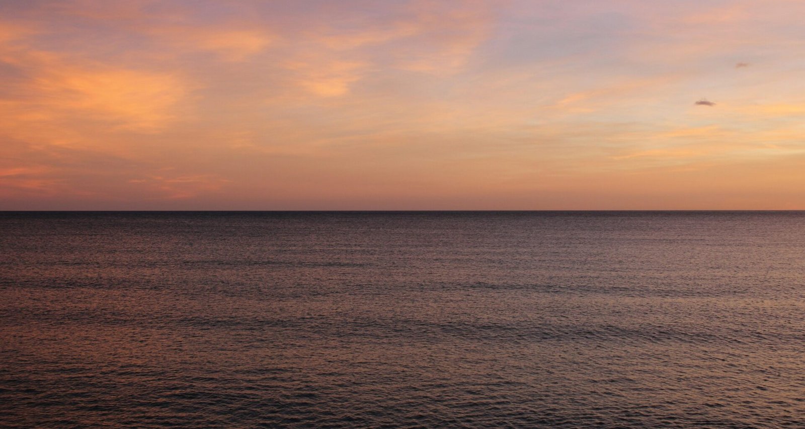 Das Meer auf Mallorca spiegelt den Sonnenuntergang wider, mit sanften Wellen und warmen Farben am Himmel.