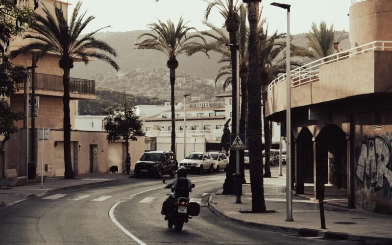 Mann fährt mit Motorrad auf Mallorca auf einer Straße bei Tageslicht, umgeben von Natur