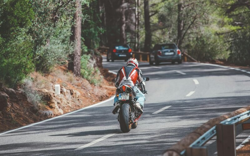 Motorradfahrer in rotem und weißem Anzug fährt auf Mallorca bei Tageslicht auf der Straße