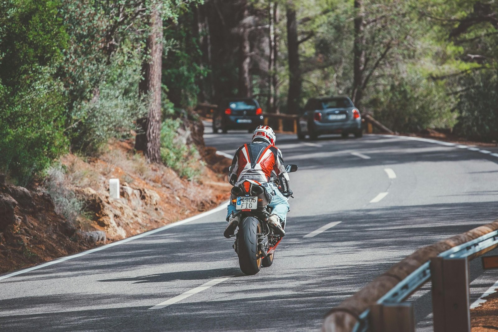 Motorradfahrer in rotem und weißem Anzug fährt auf Mallorca bei Tageslicht auf der Straße
