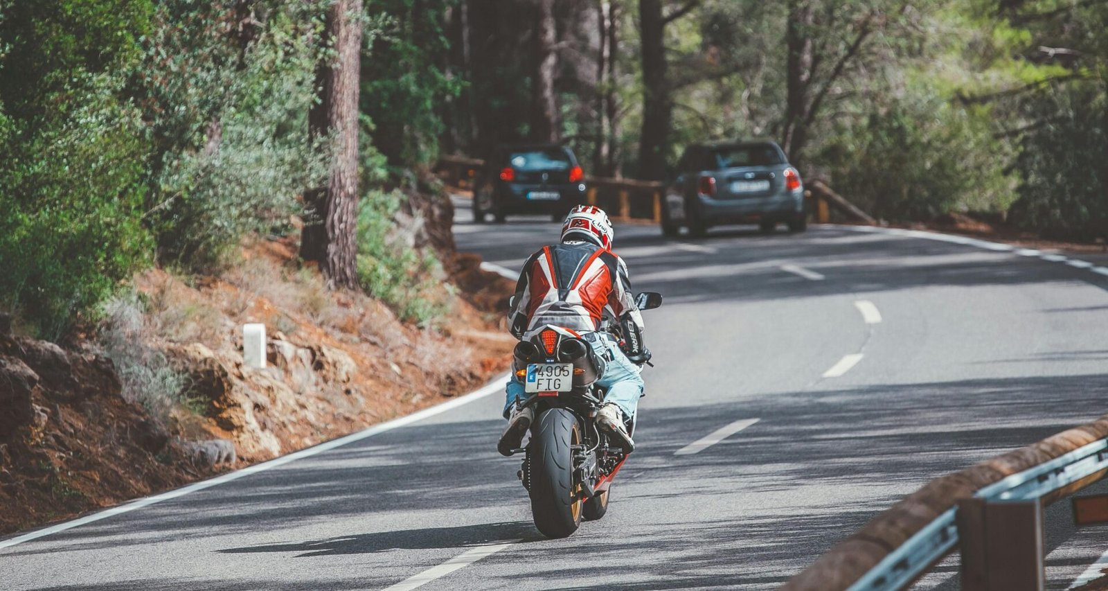 Motorradfahrer in rotem und weißem Anzug fährt auf Mallorca bei Tageslicht auf einer Straße