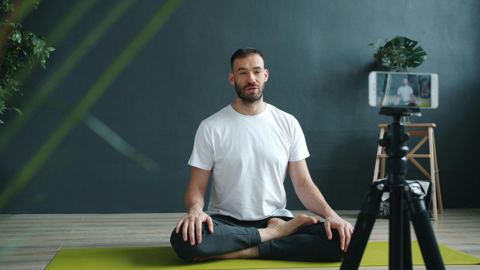 Mann meditiert auf Mallorca auf einer Yoga-Matte und filmt die Praxis mit seinem Smartphone, um Ruhe und Achtsamkeit zu dokumentieren.