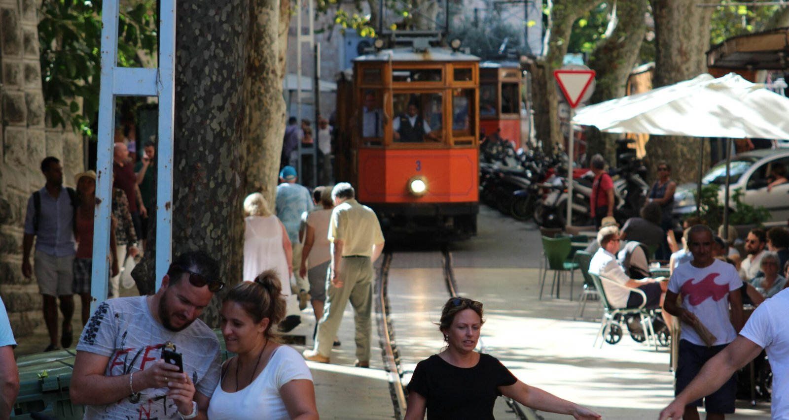 Menschen gehen tagsüber auf einer belebten Straße auf Mallorca spazieren, fotografiert von John McFetridge.