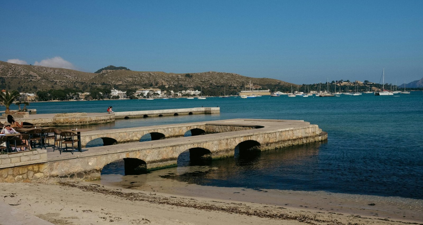 Menschen sitzen an einem Pier auf Mallorca am Wasser, fotografiert von Konstantin Chemeris