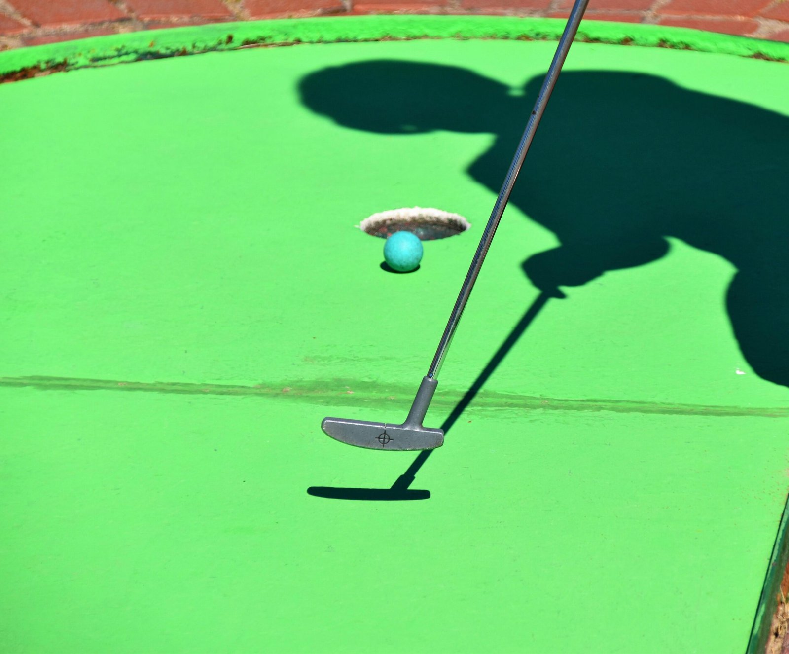 Golfer beim Abschlag auf Mallorca, Ball kurz vor dem Loch, umgeben von grünem Rasen, fotografiert von Waldemar Brandt