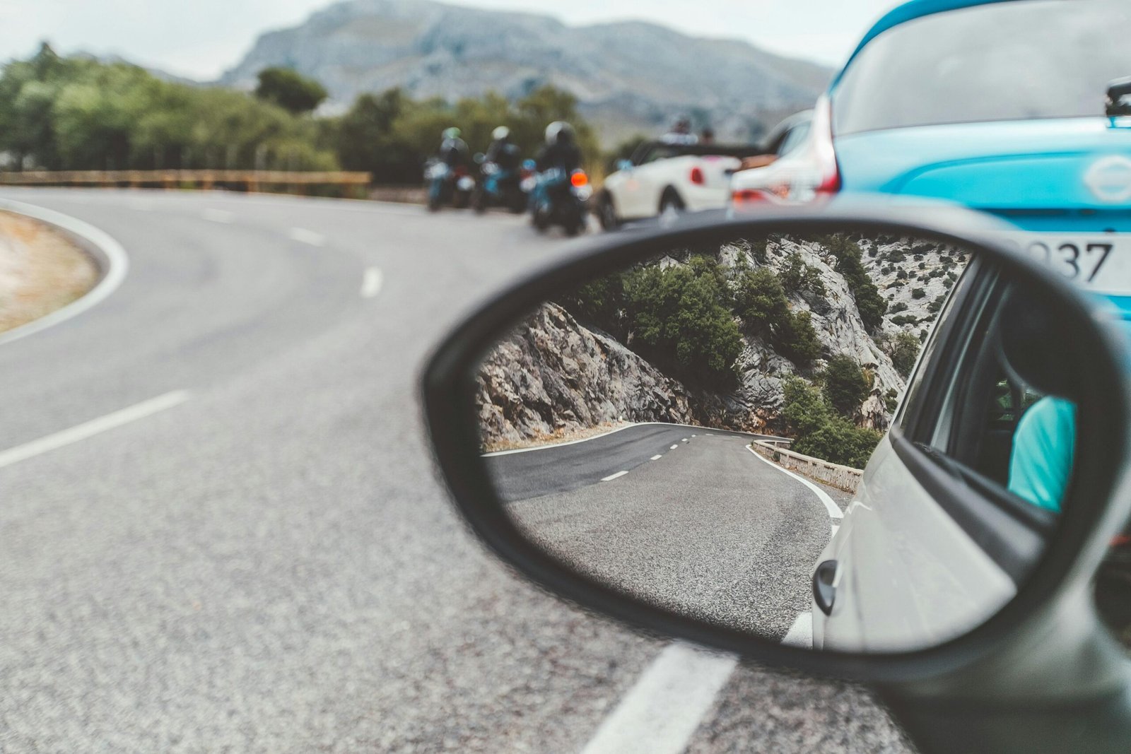 Schwarzer Autospiegel auf Mallorca zeigt vorbeifahrende Autos auf der Straße bei Tageslicht