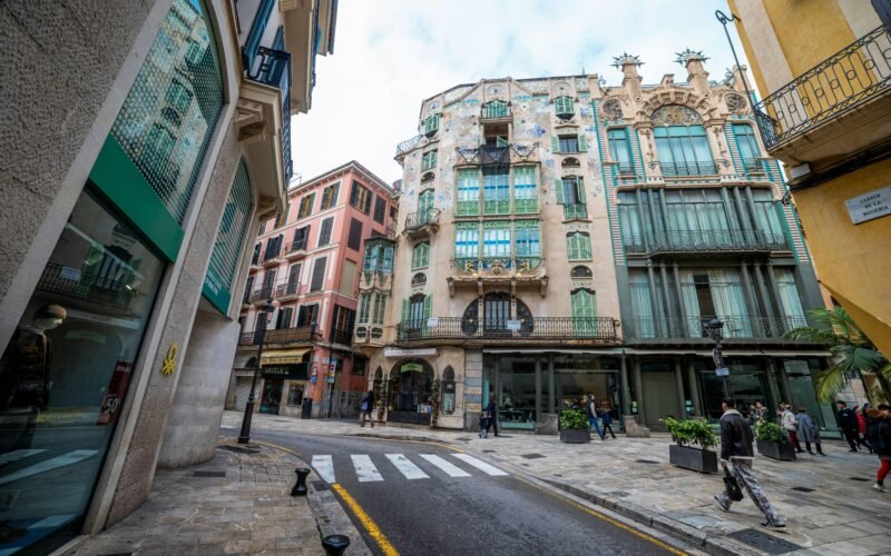 Ornate Gebäude entlang einer kopfsteingepflasterten Straße mit Zebrastreifen auf Mallorca, aufgenommen von Viacheslav Poturaev.